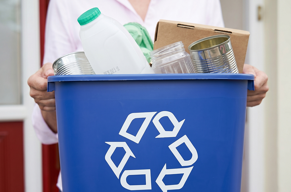 a woman holding a blue recycle bin
