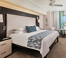 A wide view of a hotel room with a king-sized bed, desk, and window seating area.