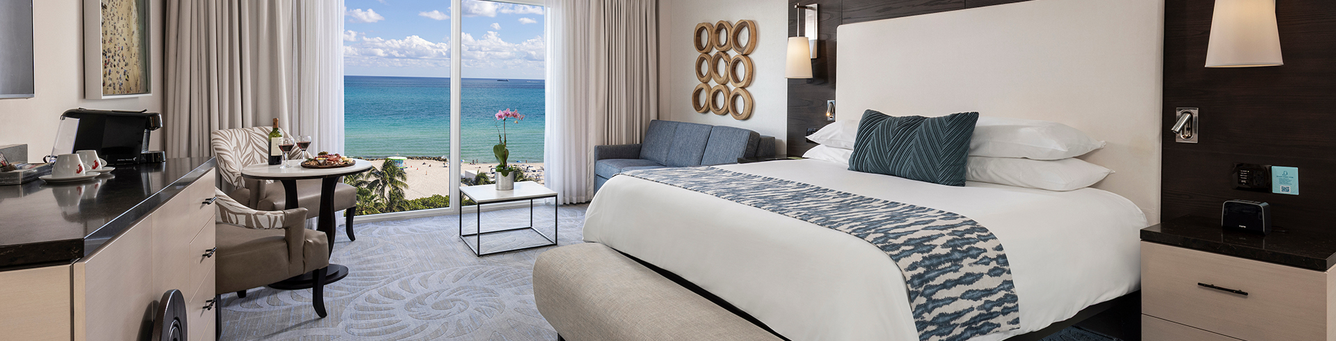 a room with a bed and a couch and a window with a view of the ocean