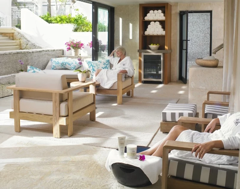 A serene spa lounge with people relaxing in robes, surrounded by wooden furniture and spa products.