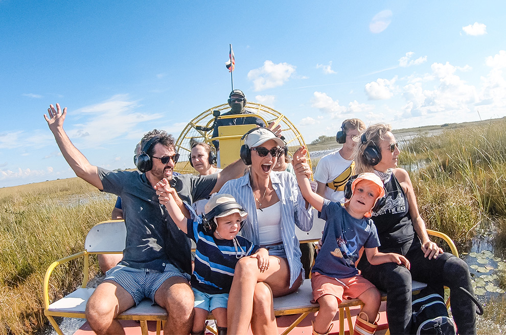 a group of people sitting on a bench with a boat in the background