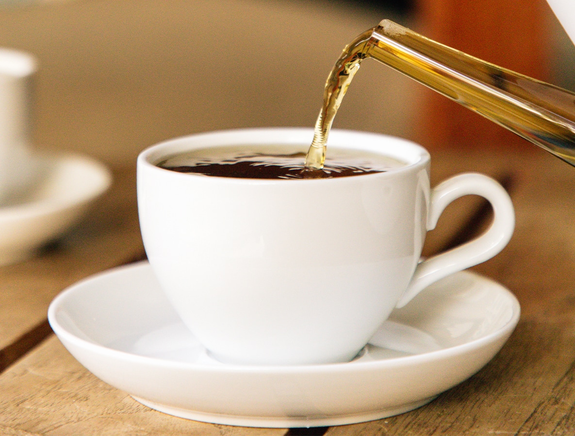 a cup of tea being poured into a white cup