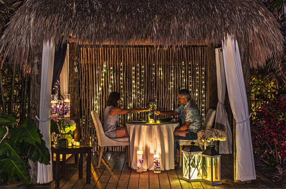 a man and woman sitting at a table with candles and lights
