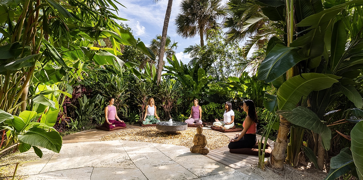 a group of women sitting in a circle in the middle of a forest