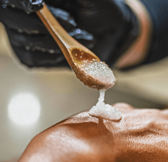 a person's hand holding a wooden spoon with a sugar on the back of their head