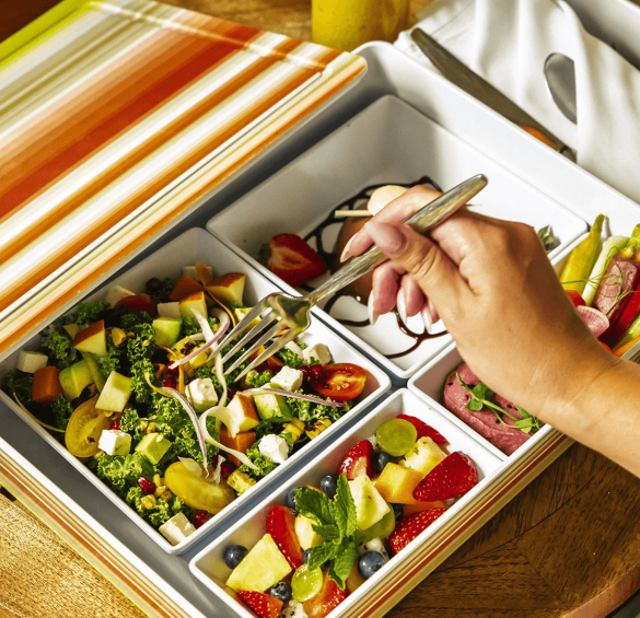 a hand holding a fork in a salad box