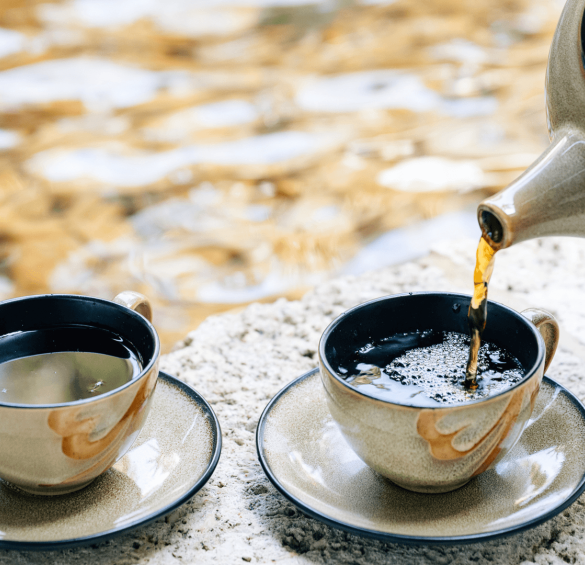 a teacups and saucers with a teapot pouring liquid into it