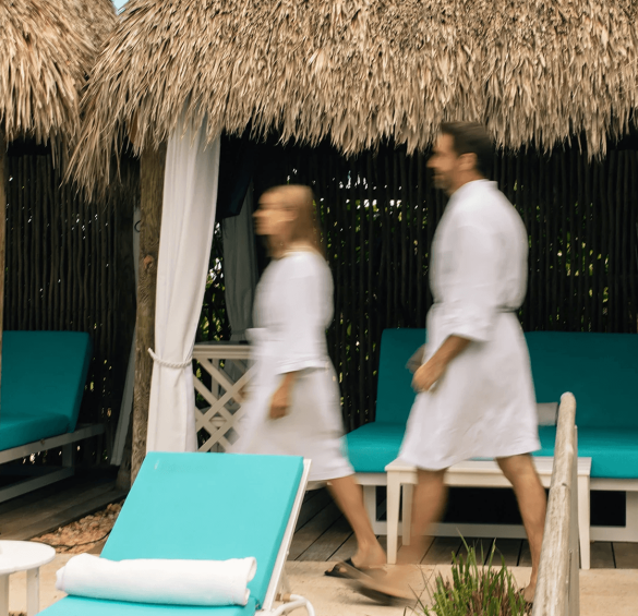 a man and woman walking near a hut