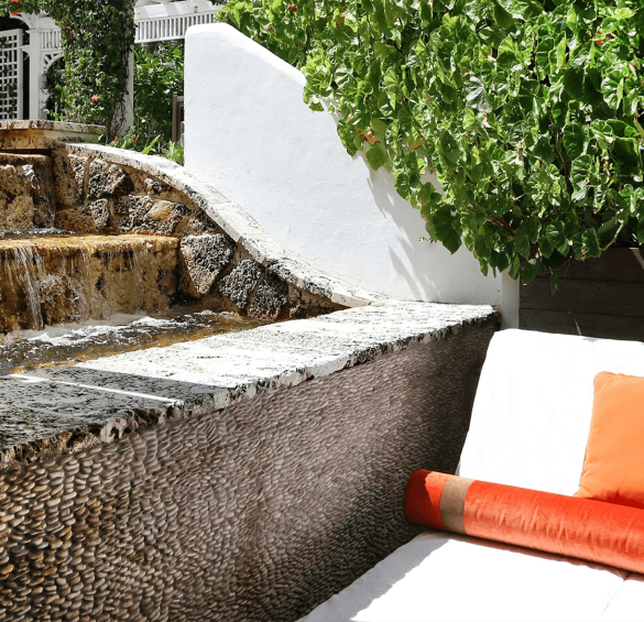 a white couch with orange pillows and a white wall with a fountain