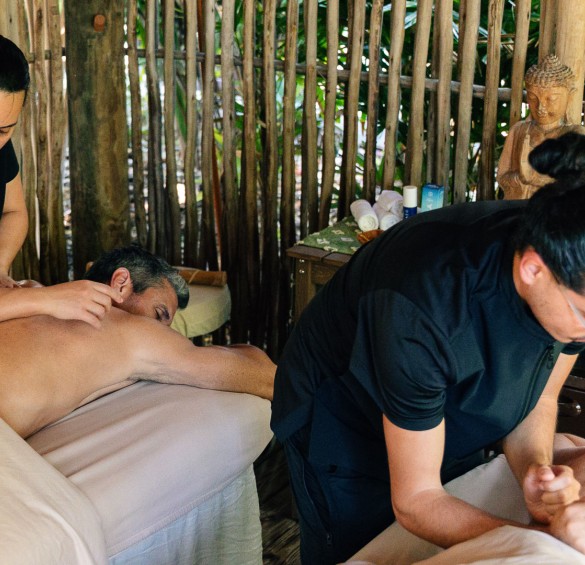 a man lying on a bed with a woman massaging another man