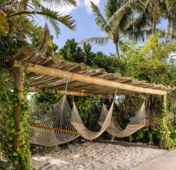hammocks on a wooden structure with a wooden structure over it and palm trees and blue sky