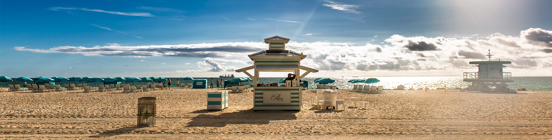 a beach with a stand and chairs and umbrellas