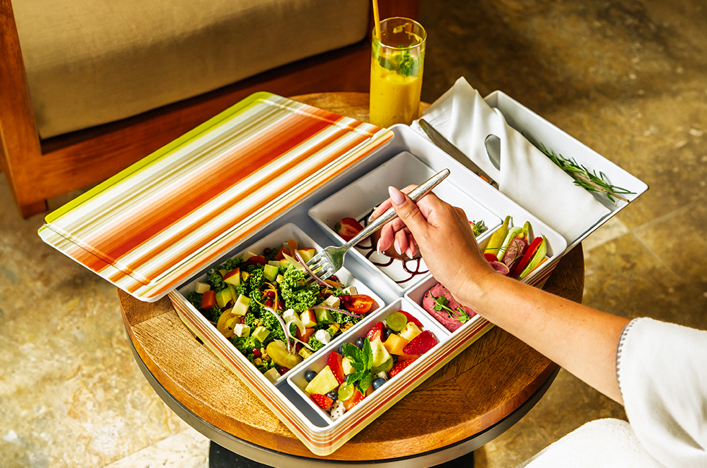 a hand holding a fork in a tray of food
