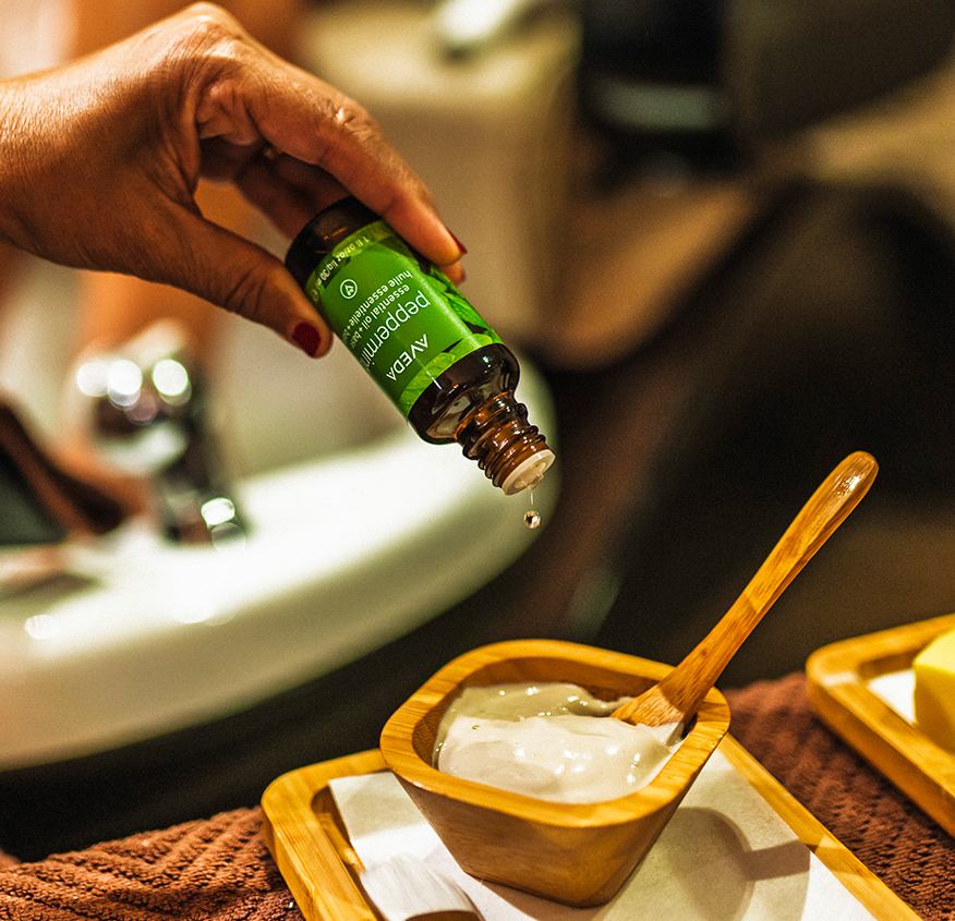 a hand pouring a drop of oil into a bowl of white liquid