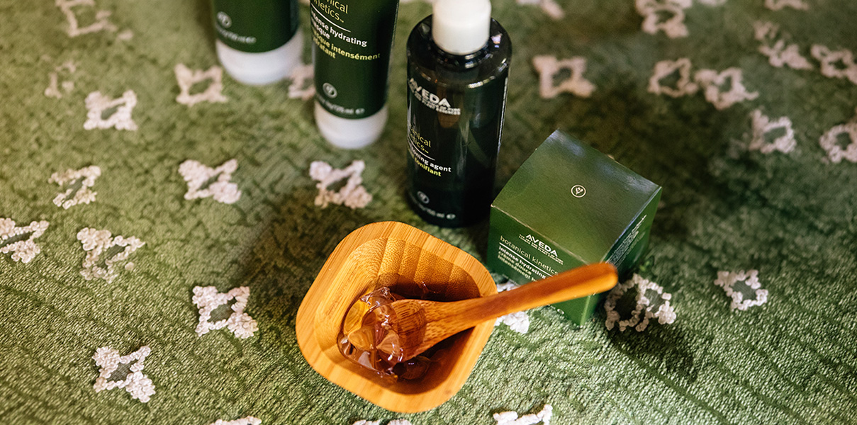 a wooden bowl with ice in it next to a wooden spoon and bottles