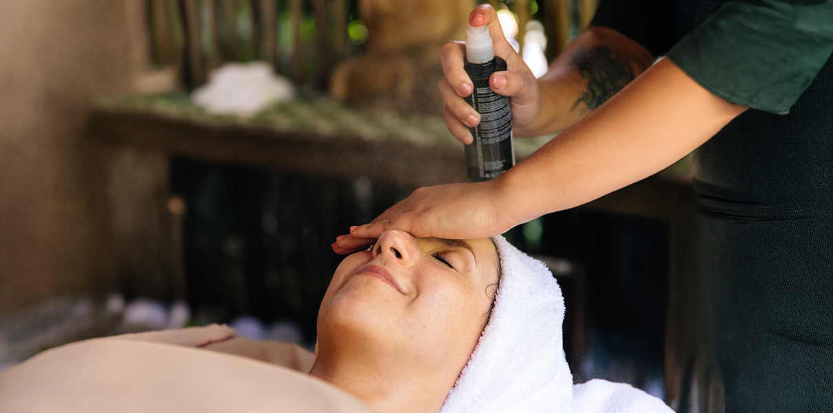 a person spraying a spray on a woman's face