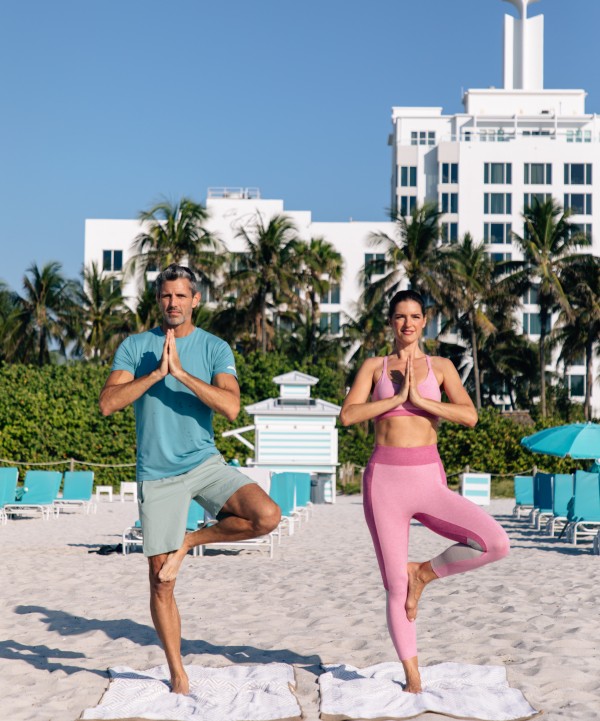 a man and woman doing yoga on a beach