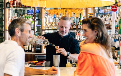 a man pouring a bottle of liquid into a glass