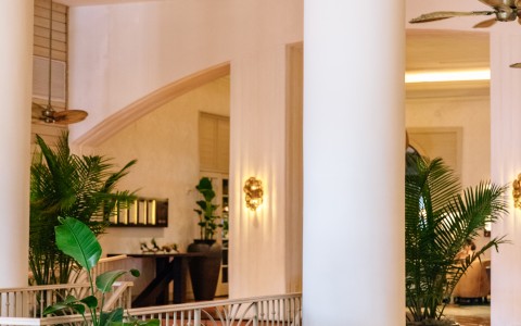 a room with white pillars and green bench