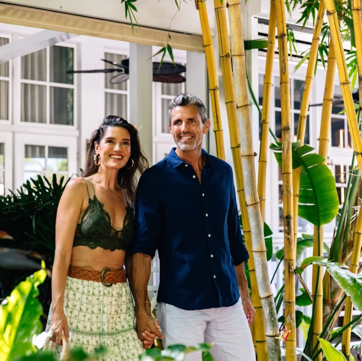 a man and woman standing next to bamboo