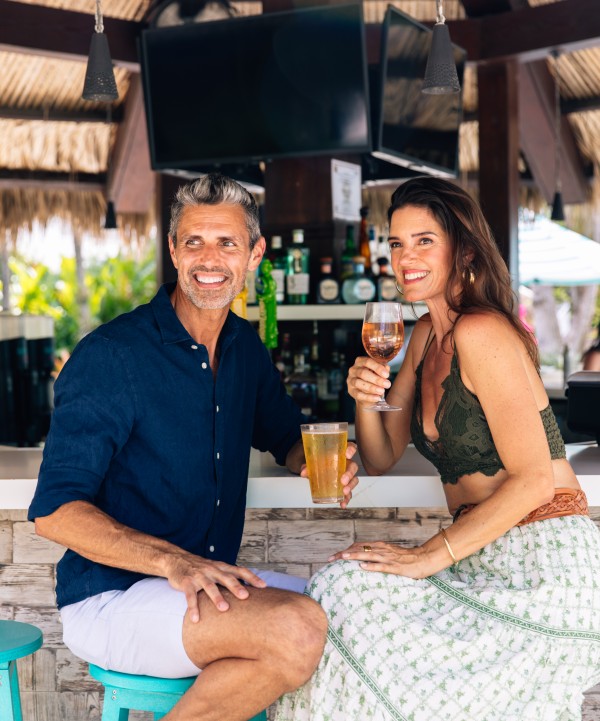 a man and woman sitting at a bar holding drinks