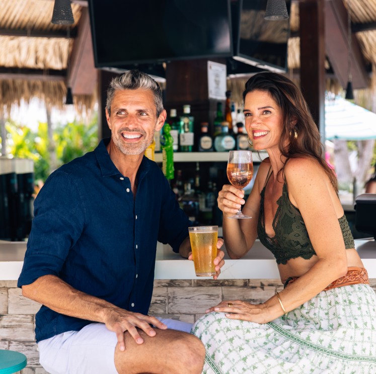 a man and woman sitting at a bar holding drinks