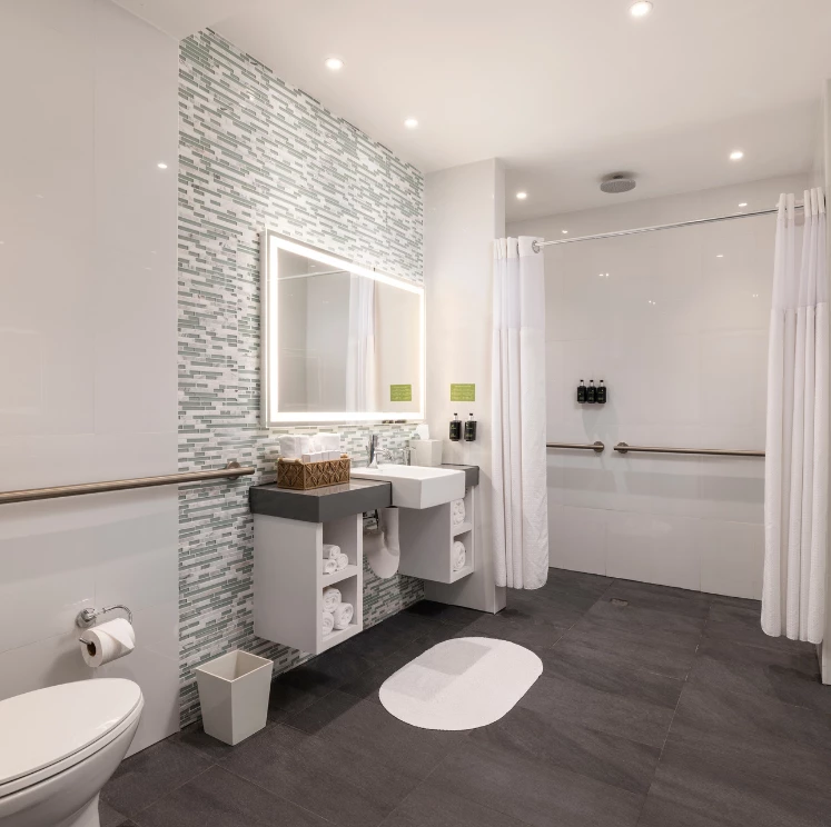 A modern hotel bathroom with a toilet, sink, and shower.