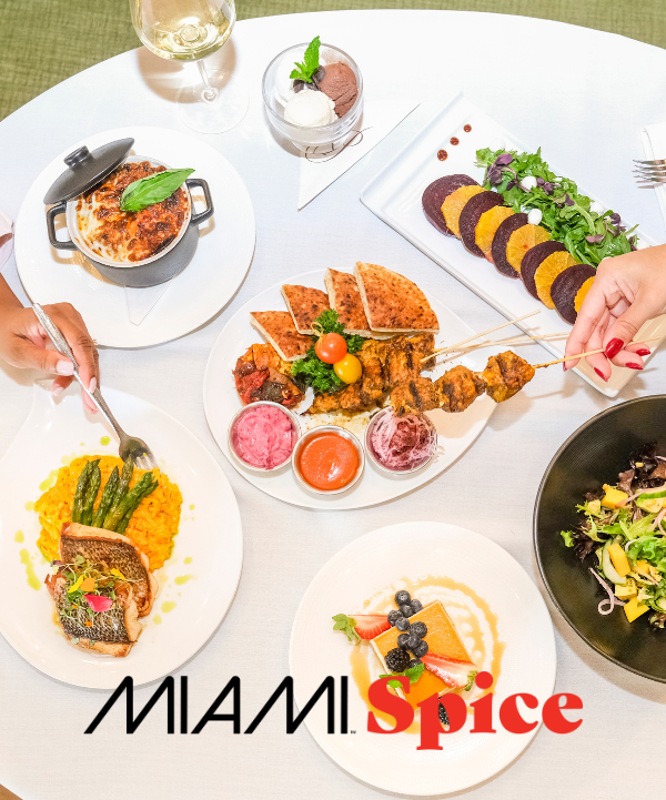 table spread of chicken kebab, fish, salad and Miami Spice logo