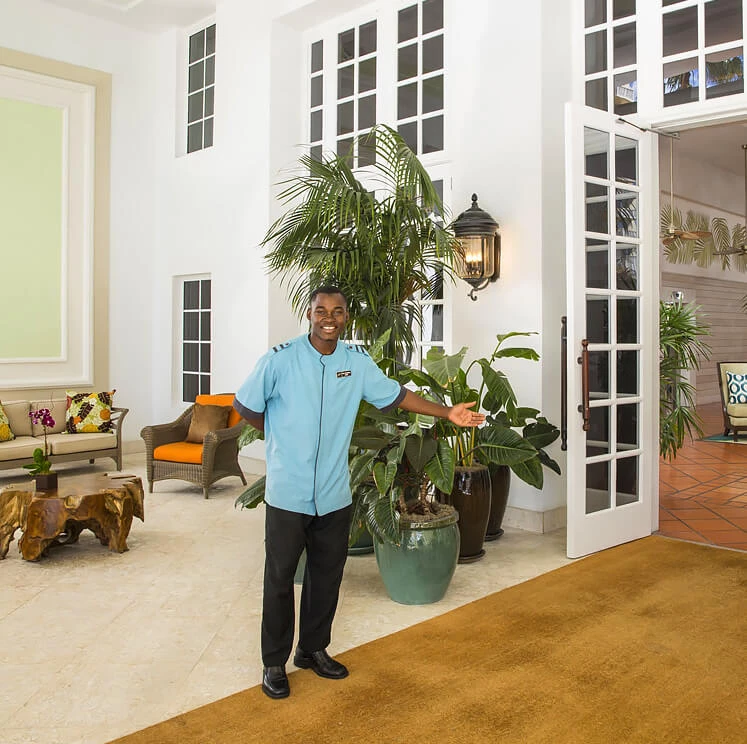A hotel lobby with a high ceiling, large windows, and plants.