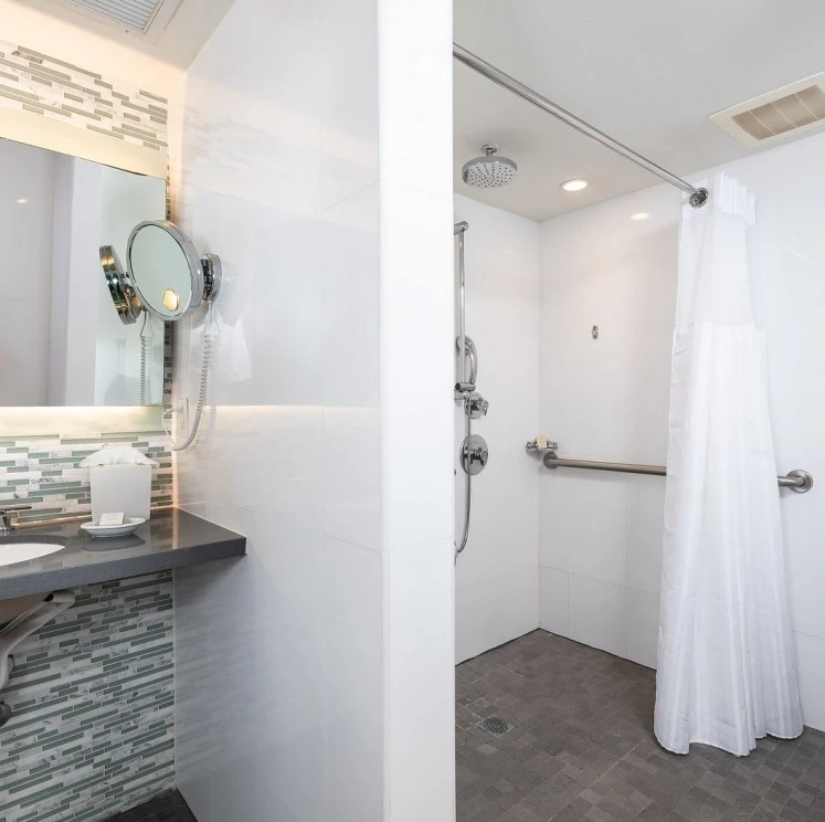 A modern hotel bathroom with a shower, sink, and mirror