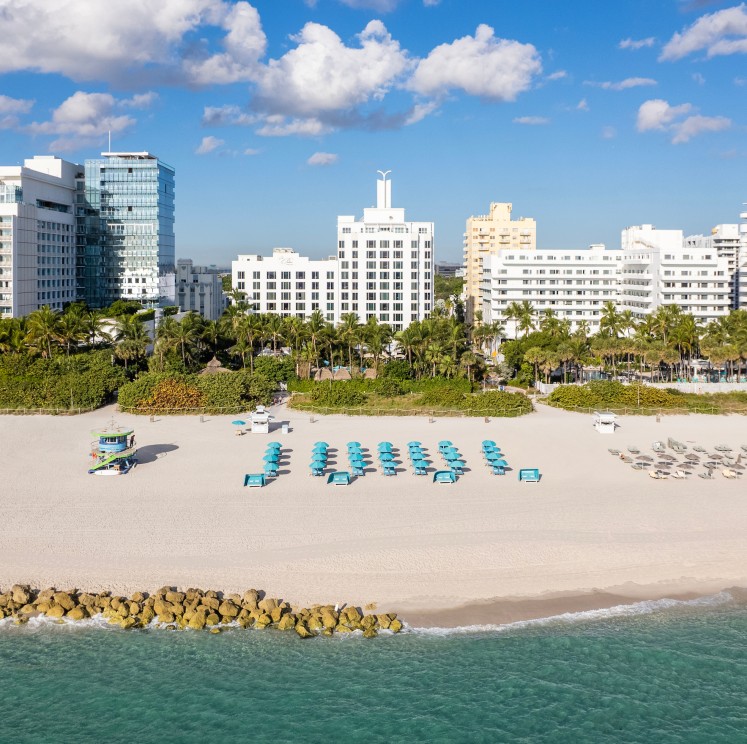 a beach with chairs and trees and buildings