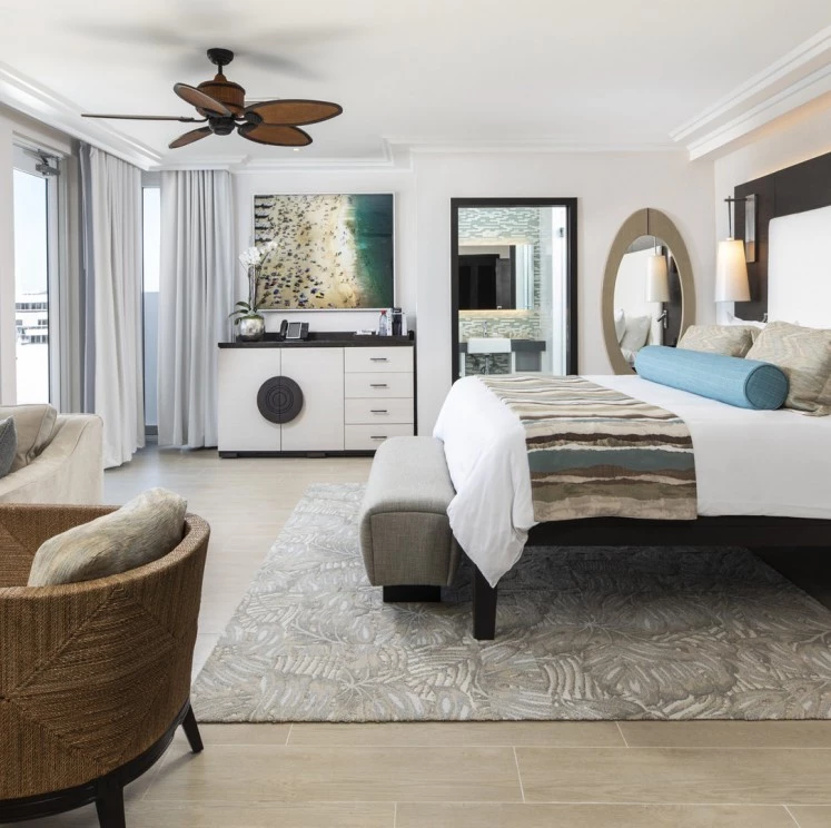A wide view of a hotel room with a large bed, sofa, and artwork.