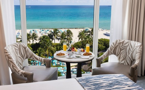 a table with food on it and chairs in front of a beach