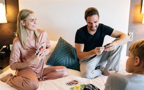 A family of three sitting on a bed in a hotel room