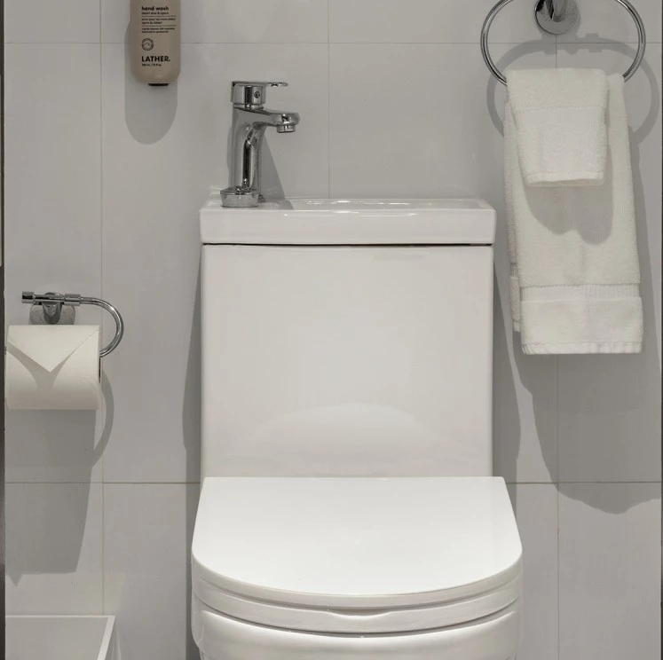A white toilet with a silver faucet and a towel rack with a white towel