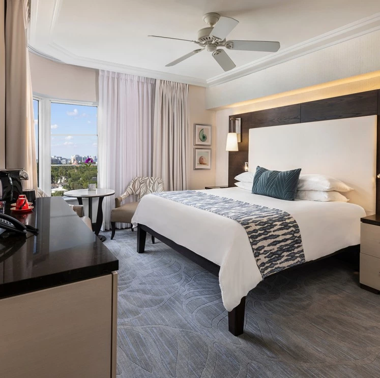 A hotel room with a large bed, desk, and window seating area.