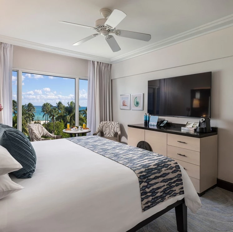 A hotel room with a large bed, ocean view, and modern amenities.