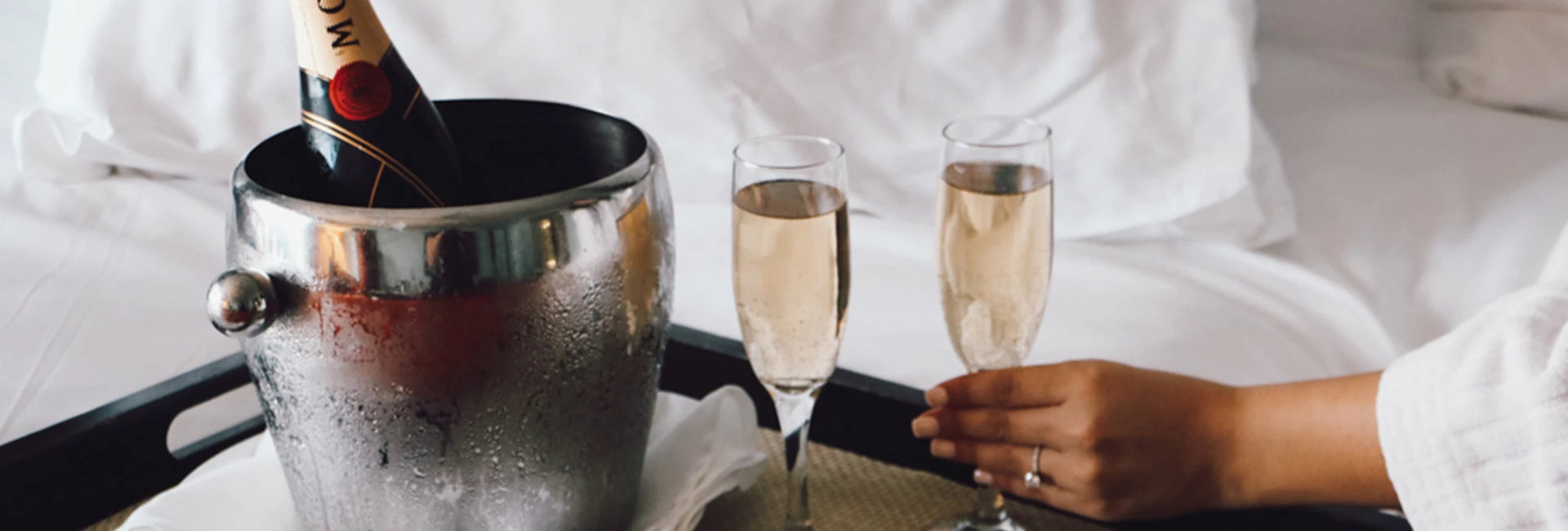 A champagne bucket with two glasses on a tray in front of a bed