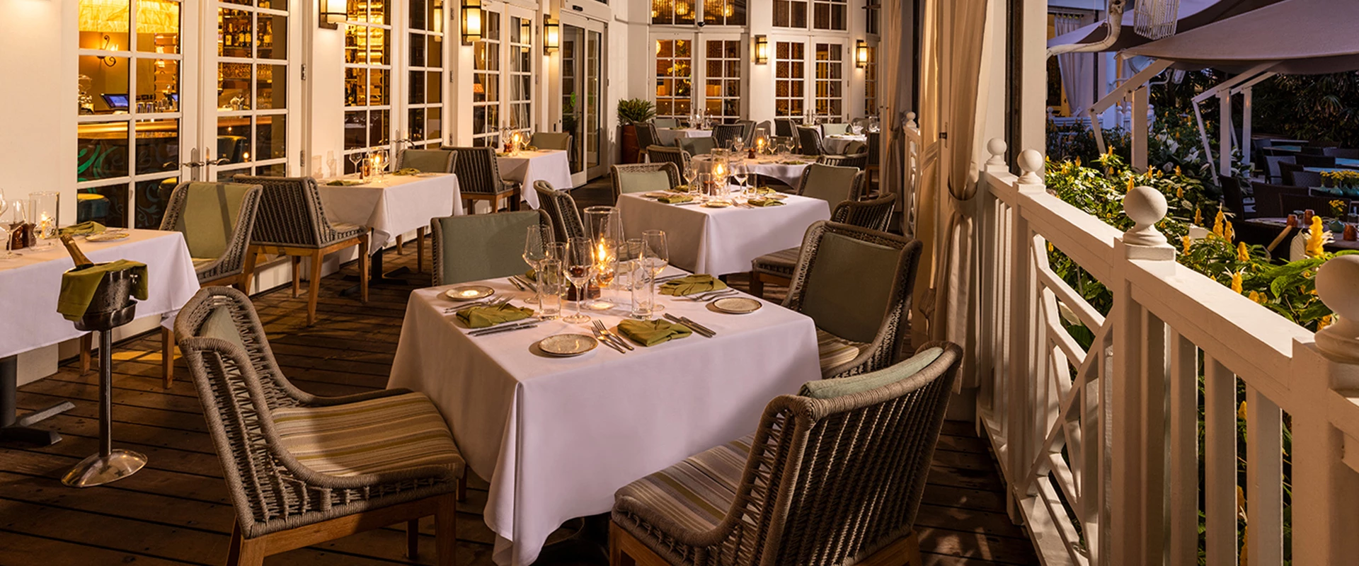 A dimly lit outdoor dining area with white tablecloths and lit candles.