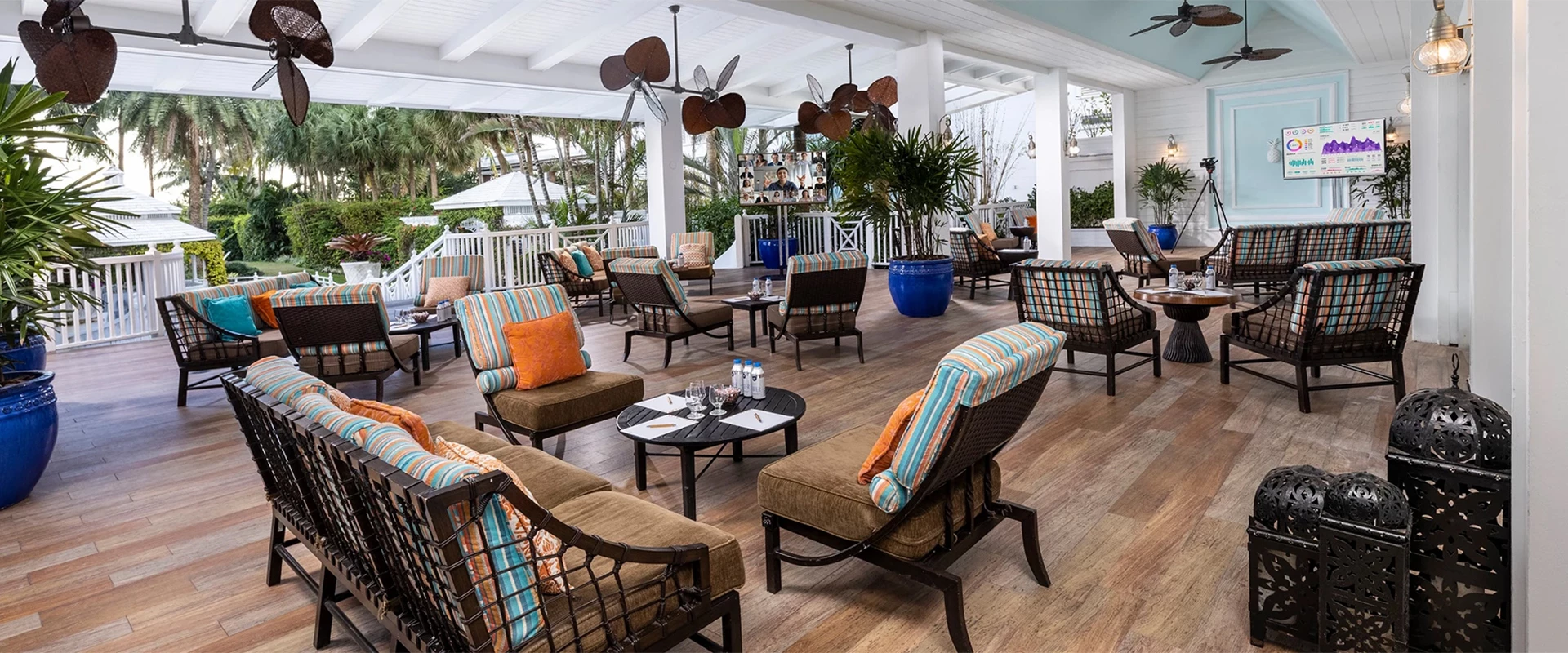 A spacious outdoor lounge area with wicker furniture and colorful pillows.