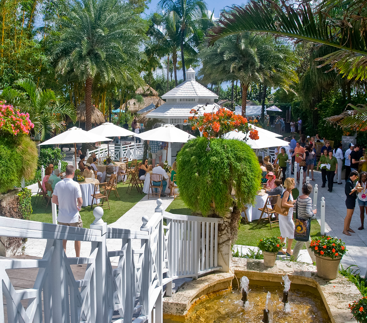 a group of people outside with umbrellas and tables and chairs