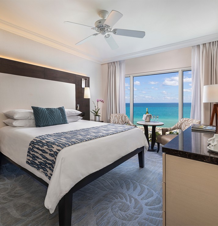 a room with a bed and a table and chairs and a window with ocean view