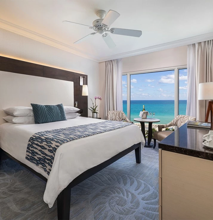 a room with a bed and a table and chairs and a window with ocean view