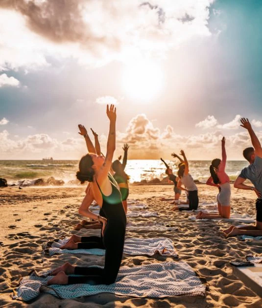 a group of people doing yoga on the beach