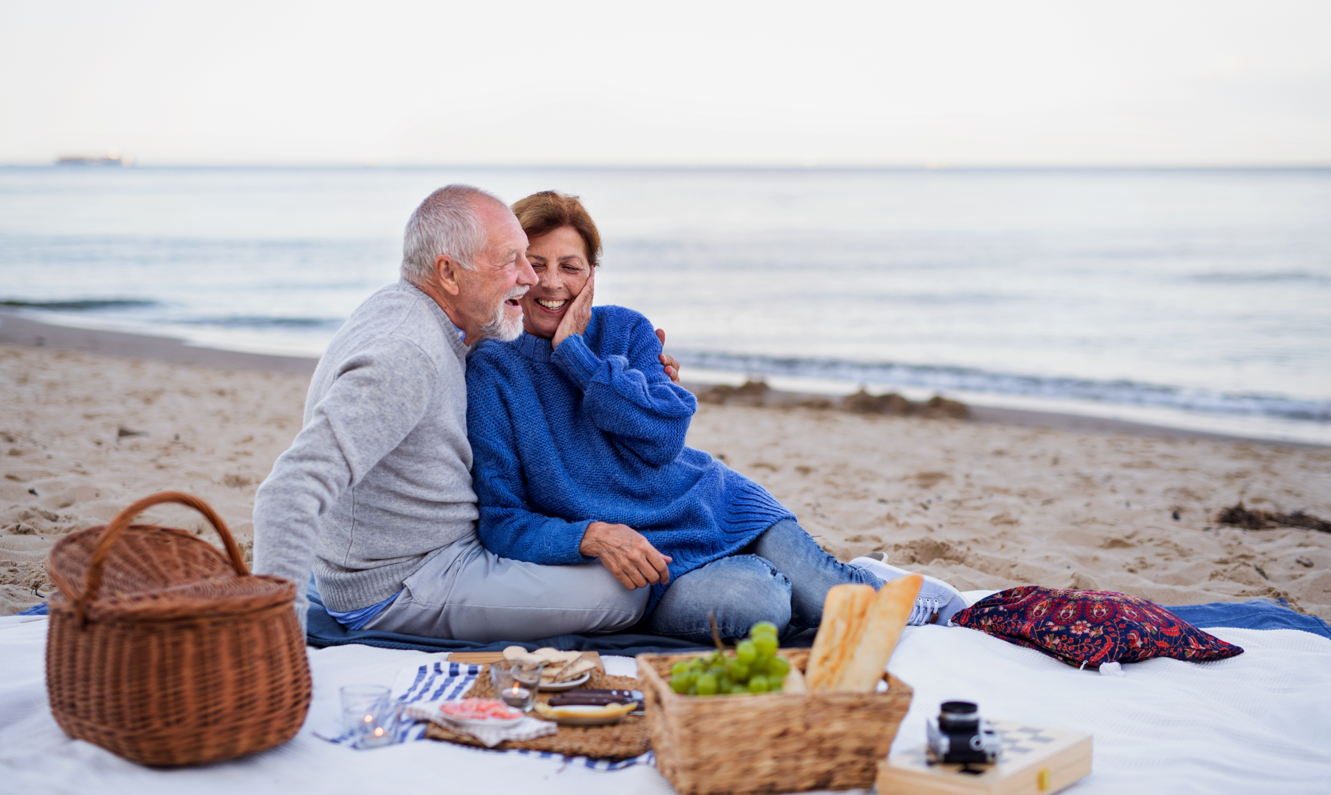 a man and woman sitting on a blanket on a beach