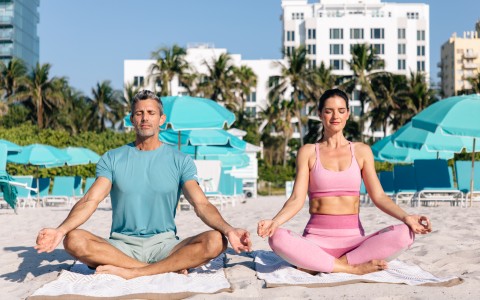 a man and woman sitting on towels on a beach