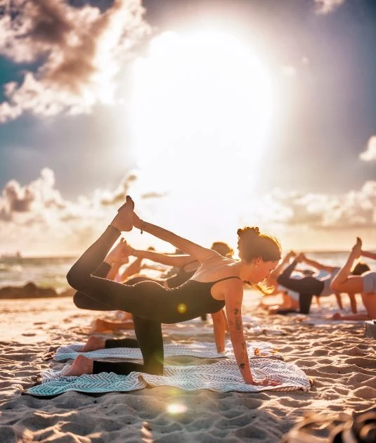 a group of people doing yoga on the beach