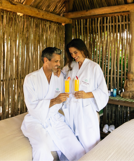 a man and woman in white robes holding glasses of orange juice