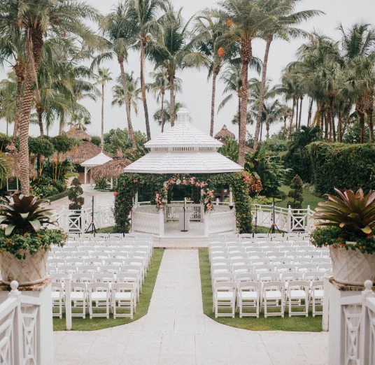 a wedding venue with white chairs and trees