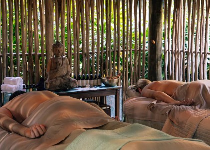 a group of people lying on beds in a room with a bamboo wall